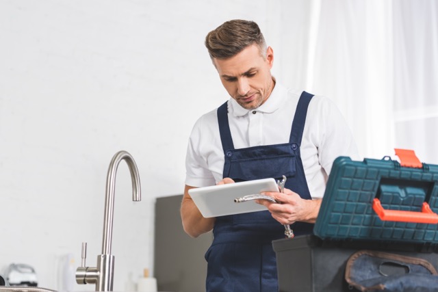 Guide to Local SEO for Plumbing Businesses: A plumber uses a tablet, showing how technology can improve plumbing services and the importance of local SEO for reaching customers.